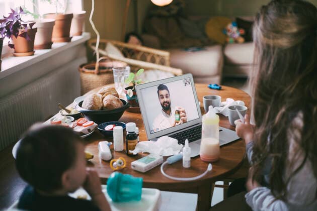 Mother taking advice from male doctor on video call through laptop in living room during COVID-19 Sweden, Stockholm, model released, property released Copyright: xMaskotx , MA85665