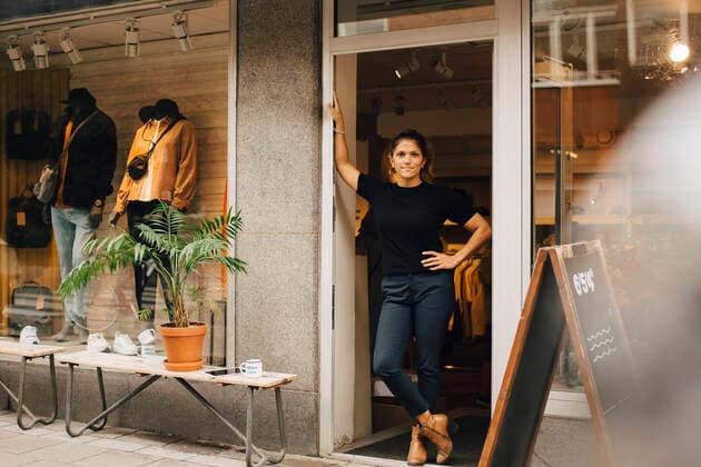 Female entrepreneur with hand on hip standing on doorway of retail store Sweden, Stockholm, model released, property released Copyright: xMaskotx , MA85327
