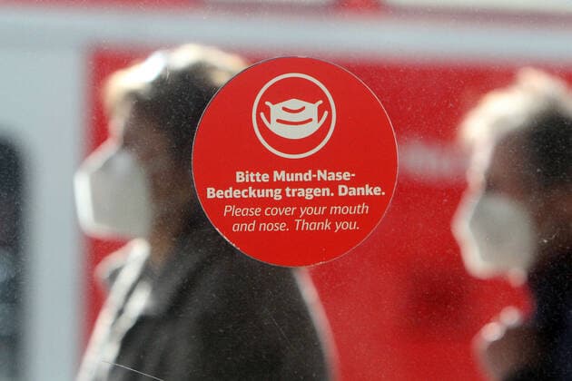Aufkleber mit Piktogramm und Aufschrift bitte Mund- Nase Bedeckung tragen klebt an einer Scheibe auf dem Bahnsteig im Hauptbahnhof von Mannheim, Baden Württemberg, Deutschland