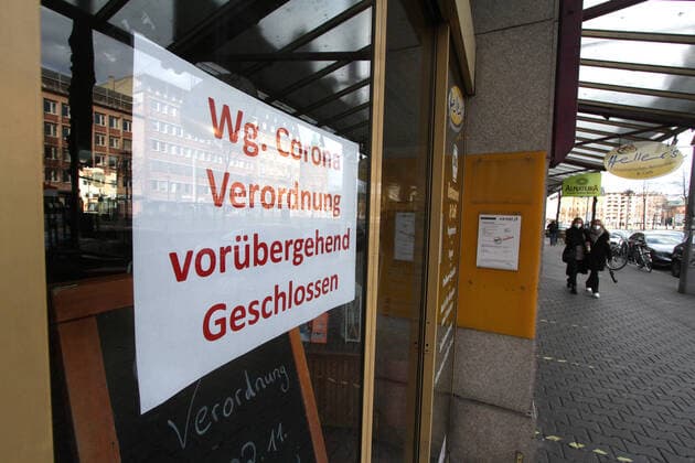 Schild mit Aufschrift wegen Corona Verordnung vorübergend geschlossen hängt an der Eingangstür eines geschlossenen Geschäfts in der Innenstadt von Mannheim, Baden Württemberg, Deutschland