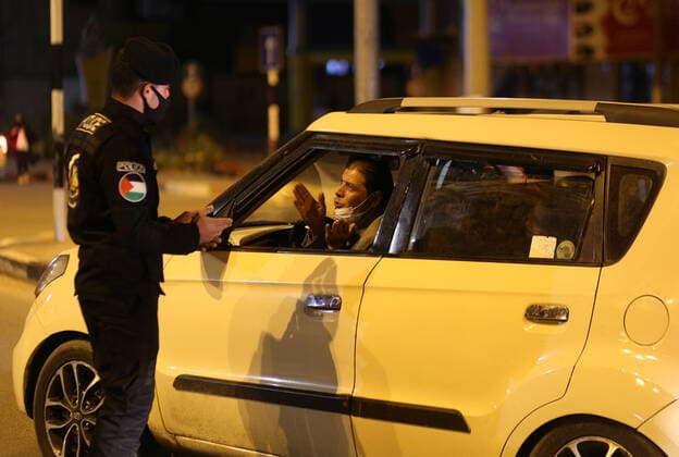 (210328) -- GAZA, March 28, 2021 -- A Palestinian police officer checks a driver in the Gaza Strip city of Khan Younis, March 27, 2021. The Hamas-run Interior Ministry imposed a full lockdown on Saturday all over the Gaza Strip at night-time from 9:00 PM due to increasing numbers of COVID-19 infection. (Photo by Xinhua) MIDEAST-GAZA-KHAN YOUNIS-COVID-19 YasserxQudih 