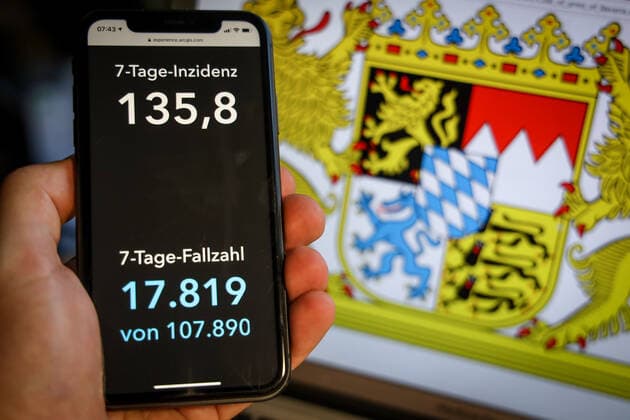 Coronavirus in Deutschland - Covid-19-Dashboard des Robert Koch-Institut DEU, Deutschland, Bayern, 28.03.2021: Die 7-Tage-Inzidenz für das Bundesland (Fälle letzte 7 Tage 100.000 EW) wird auf einem iPhone angezeigt, im Hintergrund das Landeswappen