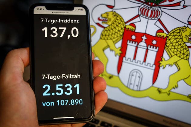 Coronavirus in Deutschland - Covid-19-Dashboard des Robert Koch-Institut DEU, Deutschland, Hamburg, 28.03.2021: Die 7-Tage-Inzidenz für das Bundesland (Fälle letzte 7 Tage 100.000 EW) wird auf einem iPhone angezeigt, im Hintergrund das Landeswappen