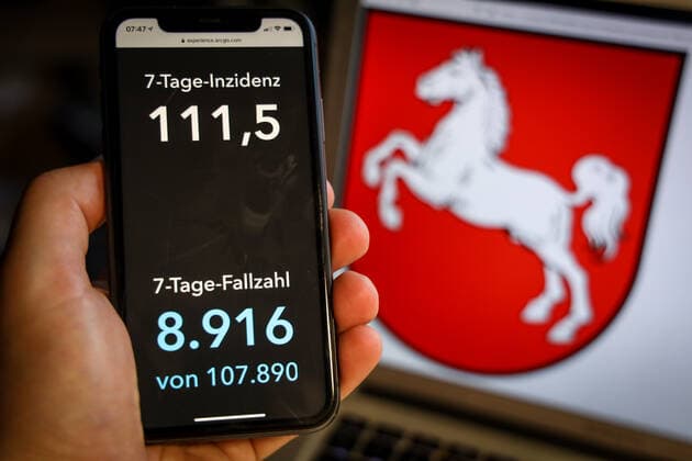 Coronavirus in Deutschland - Covid-19-Dashboard des Robert Koch-Institut DEU, Deutschland, Niedersachsen, 28.03.2021: Die 7-Tage-Inzidenz für das Bundesland (Fälle letzte 7 Tage 100.000 EW) wird auf einem iPhone angezeigt, im Hintergrund das Landeswappen