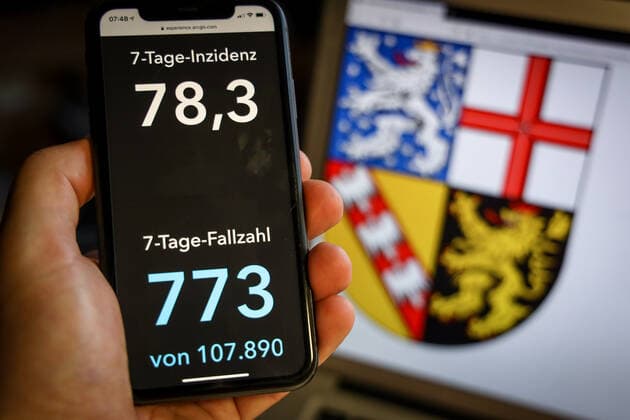 Coronavirus in Deutschland - Covid-19-Dashboard des Robert Koch-Institut DEU, Deutschland, Saarland, 28.03.2021: Die 7-Tage-Inzidenz für das Bundesland (Fälle letzte 7 Tage 100.000 EW) wird auf einem iPhone angezeigt, im Hintergrund das Landeswappen
