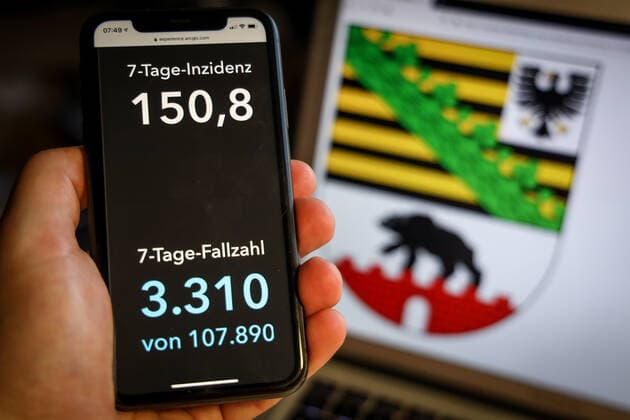 Coronavirus in Deutschland - Covid-19-Dashboard des Robert Koch-Institut DEU, Deutschland, Sachsen-Anhalt, 28.03.2021: Die 7-Tage-Inzidenz für das Bundesland (Fälle letzte 7 Tage 100.000 EW) wird auf einem iPhone angezeigt, im Hintergrund das Landeswappen