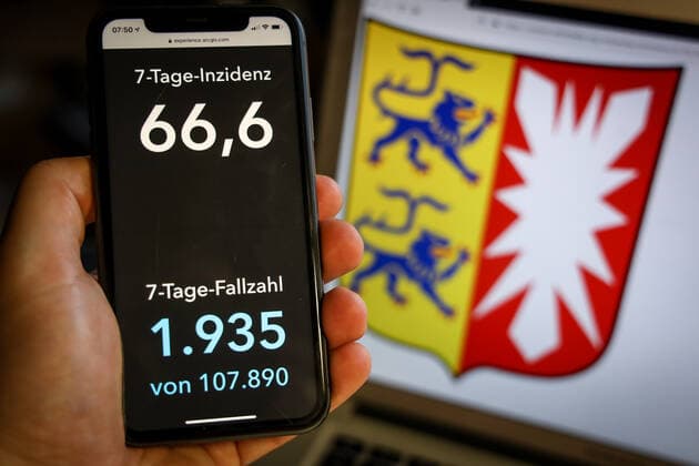 Coronavirus in Deutschland - Covid-19-Dashboard des Robert Koch-Institut DEU, Deutschland, Schleswig-Holstein, 28.03.2021: Die 7-Tage-Inzidenz für das Bundesland (Fälle letzte 7 Tage 100.000 EW) wird auf einem iPhone angezeigt, im Hintergrund das Landeswappen