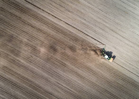 Landwirtschaft und Klimawandel, Luftbild vom Maislegen im sehr trockenen Frühjahr - landwirtschaftliches Symbolfoto. Luftaufnahme eines Schleppers mit Maislegegerät im Einsatz. Ende April bis Anfang Mai wird der Mais gelegt. Der richtige Zeitpunkt ist eine Gradwanderung - zu früh gekeimter Mais kann durch späte Nachtfröste erfrieren. Wartet man zu lange, fehlen dem Mais wichtige Tage für ein gutes Wachstum. In den letzten Jahren mit ausbleibendem Regen und Hitzeperioden entscheidet schnelles Schliessen der Maisreihen zunehmend darüber, ob ein wirtschaftlicher Maisbestand entsteht. Region Weser-Ems Niedersachsen Deutschland *** Agriculture and climate change, aerial view of maize planting in a very dry spring agricultural symbol phot