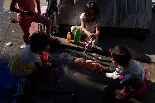March 28, 2021, Tijuana, Mexico: Children play with donated toys in a puddle on the street. Migrants from Central America are stuck living in tents on the street in Tijuana, Mexico on the border while they wait for President Joe Biden to open the American border. Tijuana Mexico - ZUMAd211 20210328_zap_d211_039 Copyright: xAllisonxDinnerx