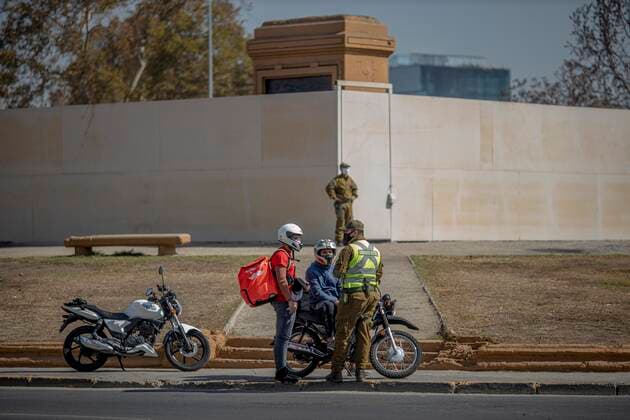 March 29, 2021, Santiago, Chile: Police officer verifies health permits for delivery drivers at a health checkpoint in Santiago..Sanitary cords and police controls during the first day of total quarantine in the central area of the country, after the abrupt increase in Covid-19 cases in the Metropolitan region, the country s health authorities decreed a total quarantine for the central area of the country. Although Chile leads the number of vaccinated population, the increase in positive cases puts the stability of the health system at risk again. Santiago Chile - ZUMAs197 20210329_zaa_s197_165 Copyright: xFelipexFigueroax