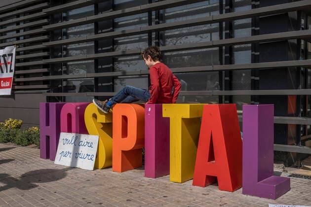 March 31, 2021, Barcelona, Catalonia, Spain: A minor playing on the hospital sign next to a placard saying I want air to live during the demonstration..Summoned by the platform against the obligation of sanitary masks in minors, El Tercer Grupo, some fifty people have gathered at the doors of the Sant Joan De Deu Children s Hospital to protest the call of the hospital to carry out tests of the covid 19 vaccine on minors. Barcelona Spain - ZUMAs197 20210331_zaa_s197_059 Copyright: xPacoxFreirex