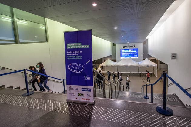 Coronavirus in Frankreich, neues Impfzentrum im Stade de France in Paris (210331) -- SAINT-DENIS (FRANCE), March 31, 2021 -- People walk past a sign of a new COVID-19 vaccination center in Saint-Denis, France, on March 31, 2021. Starting from mid-April people over 60 in France will be able to get vaccinated, from May 15 the vaccination will be open to people aged between 50 and 60 and from mid-June the age limit will be lifted, said French President Emmanuel Macron on Wednesday. (Photo by Xinhua) FRANCE-SAINT-DENIS-VACCINATION CENTER AurelienxMorissard 