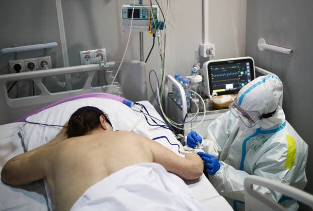 MOSCOW, RUSSIA - APRIL 1, 2021: A medical worker treats a patient at a unit of a temporary COVID-19 hospital at the Sokolniki Exhibition and Convention Center. The treatment facility has a reserve hospital and an observation center; its capacity is 550 beds, including 18 for intensive therapy patients. Sergei Bobylev TASS  TS0FB35B