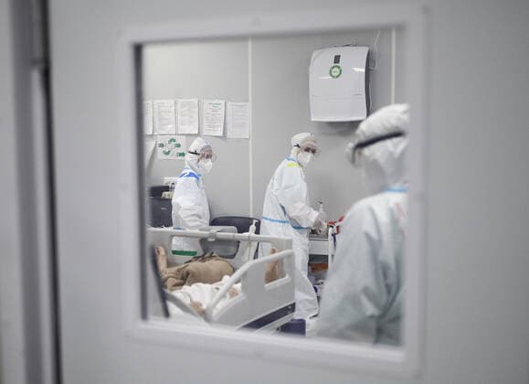 MOSCOW, RUSSIA - APRIL 1, 2021: Medical workers treat a patient at a unit of a temporary COVID-19 hospital at the Sokolniki Exhibition and Convention Center. The treatment facility has a reserve hospital and an observation center; its capacity is 550 beds, including 18 for intensive therapy patients. Sergei Bobylev TASS  TS0FB3C1