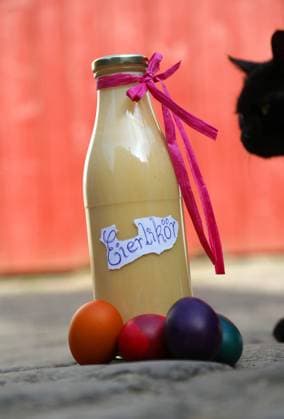 Eierlikör 01.04.2021 , Ostramondra, selbstgemachter Eierlikör und bunt gefärbte Eier, eine schwarze Katze kommt neugierig dazu *** Eggnog 01 04 2021 , Ostramondra, homemade eggnog and colorful dyed eggs, a black cat comes curiously to it