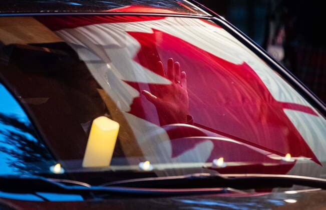April 3, 2021, North Vancouver, BC, Canada: A Canadian flag is reflected in the windshield of a car as a motorist waves to a colour guard during a drive-thru candlelight vigil for the victims of last week s mass stabbing incident in and around the Lynn Valley Library, at Lynn Canyon Park in North Vancouver, B.C., on Saturday, April 3, 2021. North Vancouver Canada  - ZUMAc35_ 20210403_zaf_c35_109 Copyright: xDarrylxDyckx