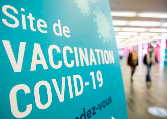 April 4, 2021, Montreal, PQ, Canada: People walk by a sign for a COVID-19 vaccination site in Montreal, Sunday, April 4, 2021. Montreal Canada  - ZUMAc35_ 20210404_zaf_c35_016 Copyright: xGrahamxHughesx