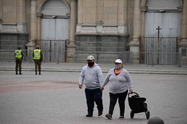 April 4, 2021, Santiago, Metropolitana, Chile: Two people with masks walk through the Plaza de Armas in Santiago, in the middle of the total quarantine decreed last week for the Metropolitan Region. Behind them the police checking the permits. Santiago Chile - ZUMAb332 20210404_zip_b332_010 Copyright: xMatiasxBasualdox