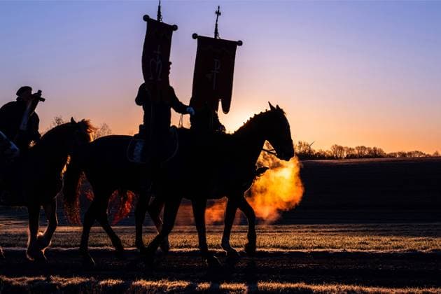 Hoch zu Ross, mit dem Kreuz, einer Statue des Auferstandenen, reiten glaeubige Katholiken waehrend des Ostersaatreitens am 04.04.2021 in der Naehe von Ostro, Sachsen. Jedes Jahr am Ostersonntag schwingen sich Scharen von Reitern in den Sattel, um ueber Felder und Fluren zu reiten. Sie sind Ostersaatreiter und verkuenden vom Pferderuecken aus die christliche Osterbotschaft, dass Jesus von den Toten auferstanden ist. Nach einer hundertjährigen Tradition reiten sorbische Maenner, meist in einem schwarzen Frack gekleidet, auf geschmueckten Pferden und verkuenden, singen und beten die Botschaft der Auferstehung Jesu. Die Sorben sind eine slawisch-deutsche Minderheit nahe der deutsch-polnischen Grenze. Men ride during the day s first procession,