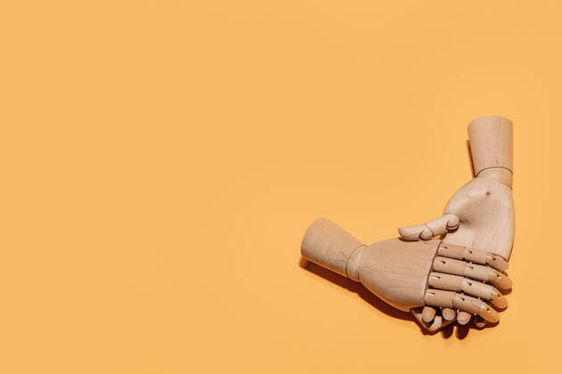 Top view of wooden hands demonstrating handshake as sign of agreement placed on yellow background Copyright: xJosexLaxx Model Released