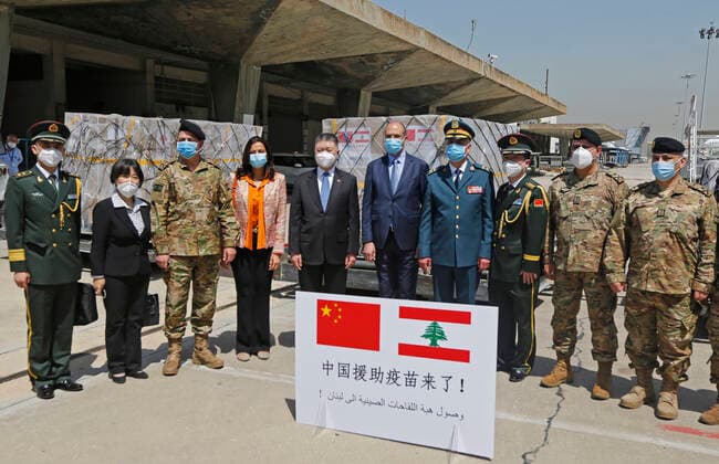 (210407) -- BEIRUT, April 7, 2021 -- Chinese Ambassador to Lebanon Wang Kejian (5th L), Lebanese Caretaker Health Minister Hamad Hassan (6th L) pose for a group photo with others in front of the Sinopharm vaccines donated by China at the Rafic Hariri International Airport in Beirut, Lebanon, April 6, 2021. Two batches of Sinopharm vaccines donated by China arrived in Lebanon on Tuesday. (Photo by Xinhua) LEBANON-BEIRUT-COVID-19-CHINESE VACCINES-ARRIVAL BilalxJawich 
