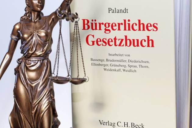 Symbolbild Gerichtsurteil: Justitia mit dem Palandt (Bürgerliches Gesetzbuch) im Hintergrund