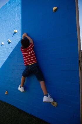 Rear view of boy climbing blue wall at playground Rear view of boy climbing blue wall at playground in school, model released, , property released, Cape Town, South Africa, 11.03.2017, 982580.jpg, climbing, wall, playground, lifestyles, leisure activity, casual clothing, gripping, striped, arms raised, sunlight, shadow, nature, challenge, child, childhood, climbing wall, conquering adversity, determination, effort, endurance, extreme sports, free climbing, reaching, risk, skill, sport, strength, success, green, school, cute, playful Outdoors,Rear view,Day,Full length