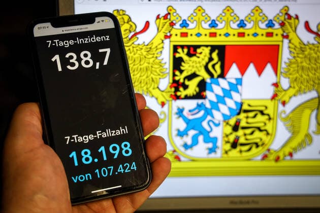 Coronavirus in Deutschland - Covid-19-Dashboard des Robert Koch-Institut DEU, Deutschland, Bayern, 11.04.2021: Die 7-Tage-Inzidenz für das Bundesland (Fälle letzte 7 Tage 100.000 EW) wird auf einem iPhone angezeigt, im Hintergrund das Landeswappen
