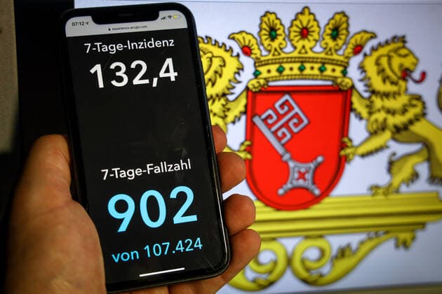 Coronavirus in Deutschland - Covid-19-Dashboard des Robert Koch-Institut DEU, Deutschland, Bremen, 11.04.2021: Die 7-Tage-Inzidenz für das Bundesland (Fälle letzte 7 Tage 100.000 EW) wird auf einem iPhone angezeigt, im Hintergrund das Landeswappen