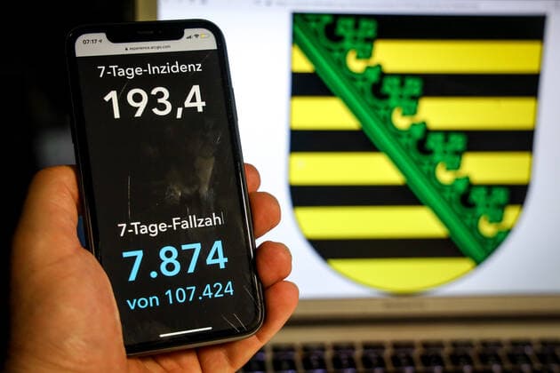 Coronavirus in Deutschland - Covid-19-Dashboard des Robert Koch-Institut DEU, Deutschland, Sachsen, 11.04.2021: Die 7-Tage-Inzidenz für das Bundesland (Fälle letzte 7 Tage 100.000 EW) wird auf einem iPhone angezeigt, im Hintergrund das Landeswappen