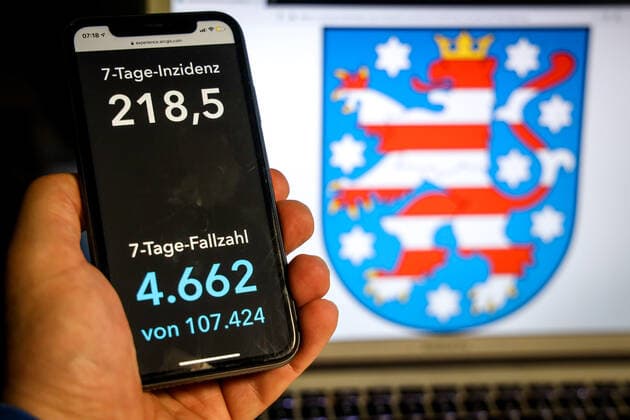Coronavirus in Deutschland - Covid-19-Dashboard des Robert Koch-Institut DEU, Deutschland, Thüringen, 11.04.2021: Die 7-Tage-Inzidenz für das Bundesland (Fälle letzte 7 Tage 100.000 EW) wird auf einem iPhone angezeigt, im Hintergrund das Landeswappen