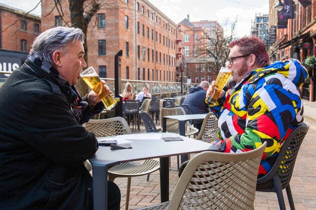 Two men enjoy their first drink of the day on Canal Street in city centre Manchester on 12 April 2021. Customers have returned to the High Street on Monday as non-essential retailers in England and Wales reopened after more than three months of lockdown restrictions due to the Covid-19 pandemic. Manchester Greater Manchester England City Centre  Copyright: xMattxWilkinsonx
