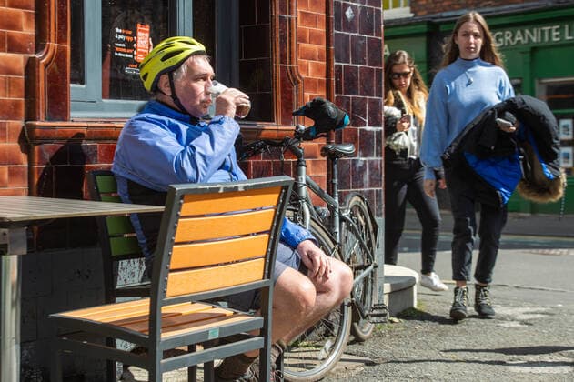 A cyclist stops for a pint outside a pub, following the relaxing of lockdown restrictions, in the sunshine in central Manchester on 12 April 2021. Customers have returned to the High Street on Monday as non-essential retailers in England and Wales reopened after more than three months of lockdown restrictions due to the Covid-19 pandemic. Manchester Greater Manchester England City Centre  Copyright: xMattxWilkinsonx