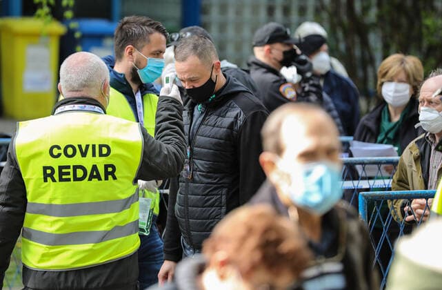 PXL_Mass vaccination in Zagreb Covid ranger measures a man s temperature in front Zagreb Fair hall during a mass vaccination at Zagreb Fair hall in Zagreb,Croatia on April 12, 2021.By the end of the day 5,000 citizens should receive the AstraZeneca COVID-19 vaccine JuricaxGaloic PIXSELL