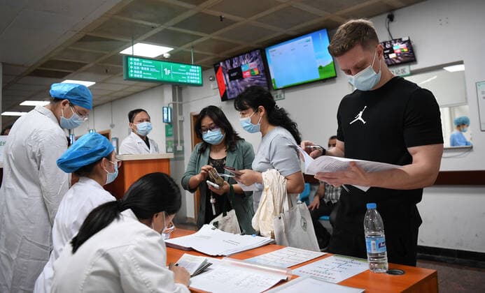 Coronavirus in China, Impfstart für Ausländer in Peking (210415) -- GUANGZHOU, April 15, 2021 -- A Ukrainian national (1st, R) registers for COVID-19 vaccination at a hospital in Yuexiu District of Guangzhou, south China s Guangdong Province, April 15, 2021. Guangdong Province started administering COVID-19 vaccines to foreigners in the province on April 15 on a voluntary basis. Foreign nationals who are covered by the local health insurance program can be vaccinated for free, enjoying the same policy as insured Chinese citizens, and those not covered will be charged 100 yuan (about 15 U.S. dollars) per dose. ) CHINA-GUANGDONG-FOREIGNERS-COVID-19-VACCINATION (CN) DengxHua 