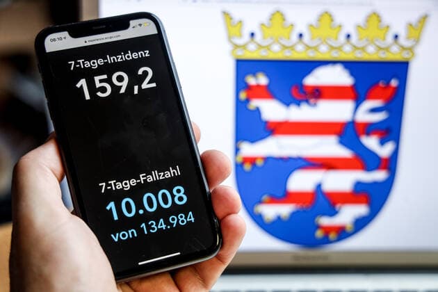 Coronavirus in Deutschland - Covid-19-Dashboard des Robert Koch-Institut DEU, Deutschland, Hessen, 18.04.2021: Die 7-Tage-Inzidenz für das Bundesland (Fälle letzte 7 Tage 100.000 EW) wird auf einem iPhone angezeigt, im Hintergrund das Landeswappen