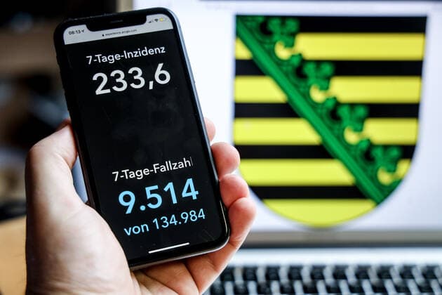 Coronavirus in Deutschland - Covid-19-Dashboard des Robert Koch-Institut DEU, Deutschland, Sachsen, 18.04.2021: Die 7-Tage-Inzidenz für das Bundesland (Fälle letzte 7 Tage 100.000 EW) wird auf einem iPhone angezeigt, im Hintergrund das Landeswappen