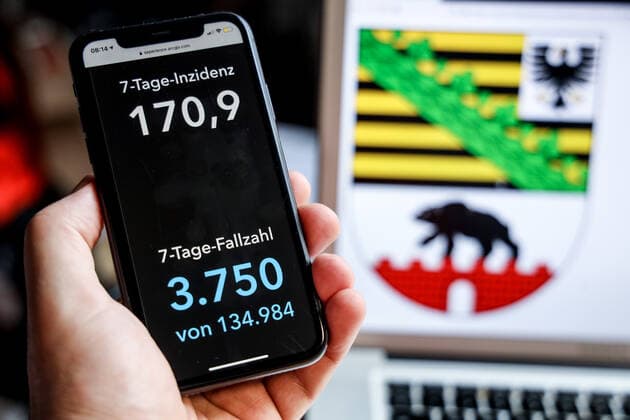 Coronavirus in Deutschland - Covid-19-Dashboard des Robert Koch-Institut DEU, Deutschland, Sachsen-Anhalt, 18.04.2021: Die 7-Tage-Inzidenz für das Bundesland (Fälle letzte 7 Tage 100.000 EW) wird auf einem iPhone angezeigt, im Hintergrund das Landeswappen