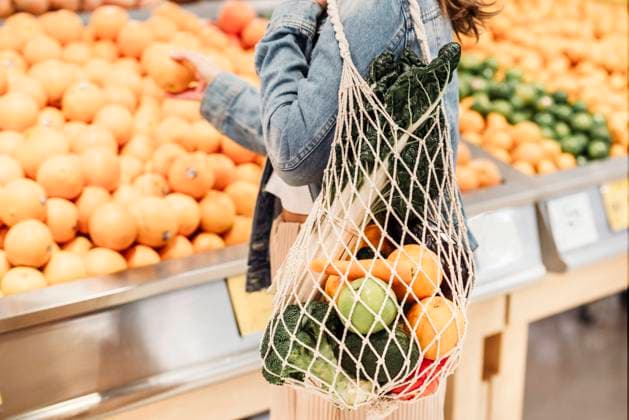 IMAGO Creative: Veganuary, fleischlos leben Side view of crop unrecognizable female buyer standing in supermarket with eco friendly mesh bag full of ripe fruits and vegetables Copyright: xAlexxBascuasx Model Released