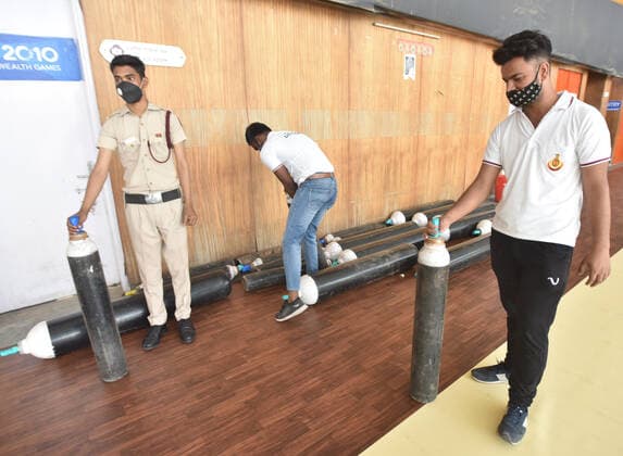 NEW DELHI, INDIA - APRIL 19: The security personnel and workers hold oxygen cylinders to set inside the newly converted COVID-19 care centre at Yamuna Sports Complex on April 19, 2021 in New Delhi, India. (Photo By Sonu Mehta Hindustan Times) Temporary Covid Care Centers Prepared In Delhi
