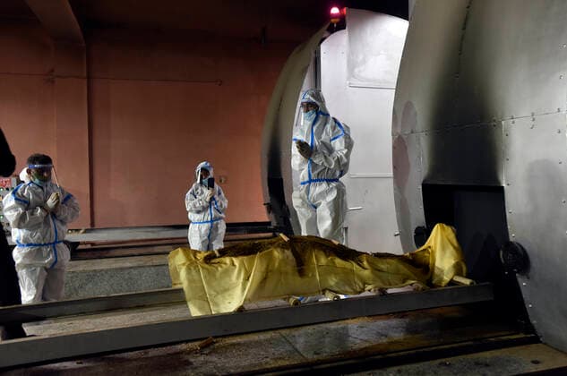 NEW DELHI, INDIA - APRIL 20: Relative of a Covid-19 victim performs the last rites, at Nigambodh Ghat crematorium on April 20, 2021 in New Delhi, India. India reports 1,761 COVID-19 deaths in the past 24 hours the highest daily toll since the pandemic erupted. (Photo by Sanjeev Verma Hindustan Times) Cremation Of Covid Victims