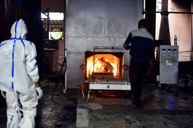 NEW DELHI, INDIA - APRIL 20: Relative of a Covid-19 victim looks on during the cremation, at Nigambodh Ghat crematorium on April 20, 2021 in New Delhi, India. India reports 1,761 COVID-19 deaths in the past 24 hours the highest daily toll since the pandemic erupted. (Photo by Sanjeev Verma Hindustan Times) Cremation Of Covid Victims