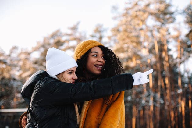 IMAGO Creative: Countdown bis Weihnachten, Nach Hause reisen Young woman pointing standing with her girlfriend outdoors in winter CR_DMBE210422-676738-01 ,model released, Symbolfoto