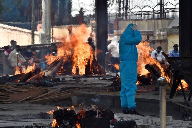 NEW DELHI, INDIA - APRIL 22: A relative of a Covid-19 victim in PPE coveralls performs the last rites, at Nigambodh Ghat crematorium, on April 22, 2021 in New Delhi, India. (Photo by Ajay Aggarwal Hindustan Times) Covid Death Toll Continues To Rise In India
