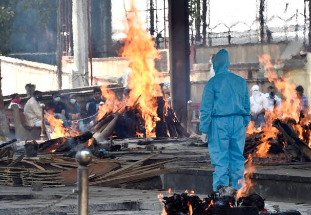 NEW DELHI, INDIA - APRIL 22: A relative of a Covid-19 victim in PPE coveralls performs the last rites, at Nigambodh Ghat crematorium, on April 22, 2021 in New Delhi, India. (Photo by Ajay Aggarwal Hindustan Times) Covid Death Toll Continues To Rise In India