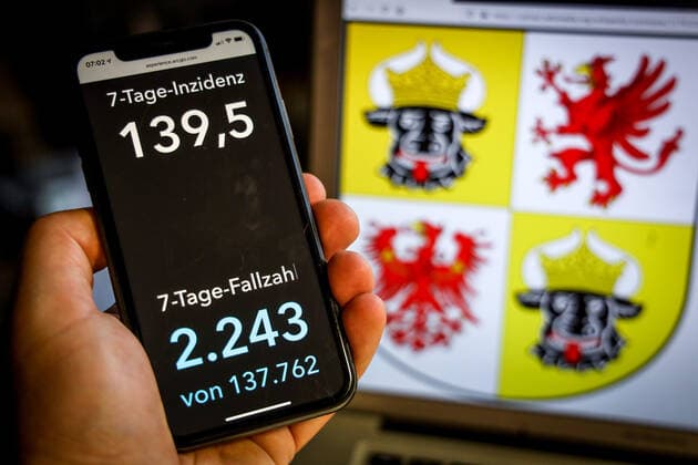 Coronavirus in Deutschland - Covid-19-Dashboard des Robert Koch-Institut DEU, Deutschland, Mecklenburg-Vorpommern, 25.04.2021: Die 7-Tage-Inzidenz für das Bundesland (Fälle letzte 7 Tage 100.000 EW) wird auf einem iPhone angezeigt, im Hintergrund das Landeswappen