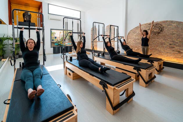 Company of females in sportswear stretching body on pilates reformers during training under supervision of professional instructor, Model released Copyright: xEnriquexEspinosax MR