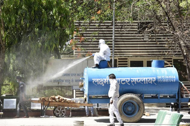 NOIDA, INDIA APRIL 25: Health worker personnel sanitize the premises of a crematorium at sector 94, on April 25, 2021 in Noida, India. (Photo by Sunil Ghosh Hindustan Times ) Covid Death Toll Continues To Rise In India