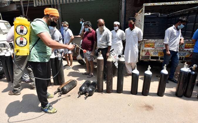 NEW DELHI, INDIA - APRIL 26: Family members of patients stand with empty oxygen cylinders outside the oxygen filling center at Bhogal on April 26, 2021 in New Delhi, India. (Photo By Sonu Mehta Hindustan Times) India Faces Oxygen Crisis As Covid-19 Cases Mount