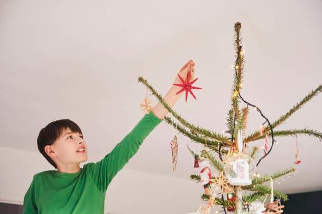 Boy decorating Christmas tree at home model released Symbolfoto property released PWF00294